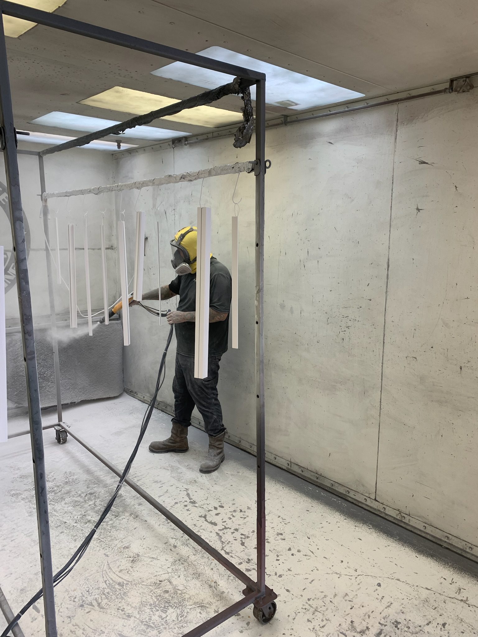 H-Town Coaters technicians in Houston applying powder coating and inspecting finished metal components — showcasing precision application, curing, and quality control for architectural and industrial projects.